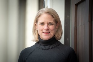 Headshot of Leslie Hawes, Executive Director of Court Watch Montgomery, a person with short blonde hair wearing red lipstick and a black turtleneck sweater