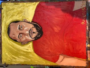 Painting of a man with short black hair against a yellow background. He is wearing a red shirt.