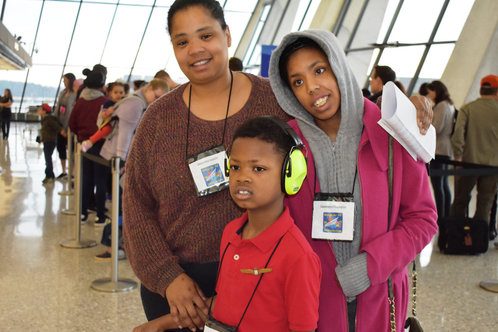 Photo of a family of three posing for the camera in line at an airport
