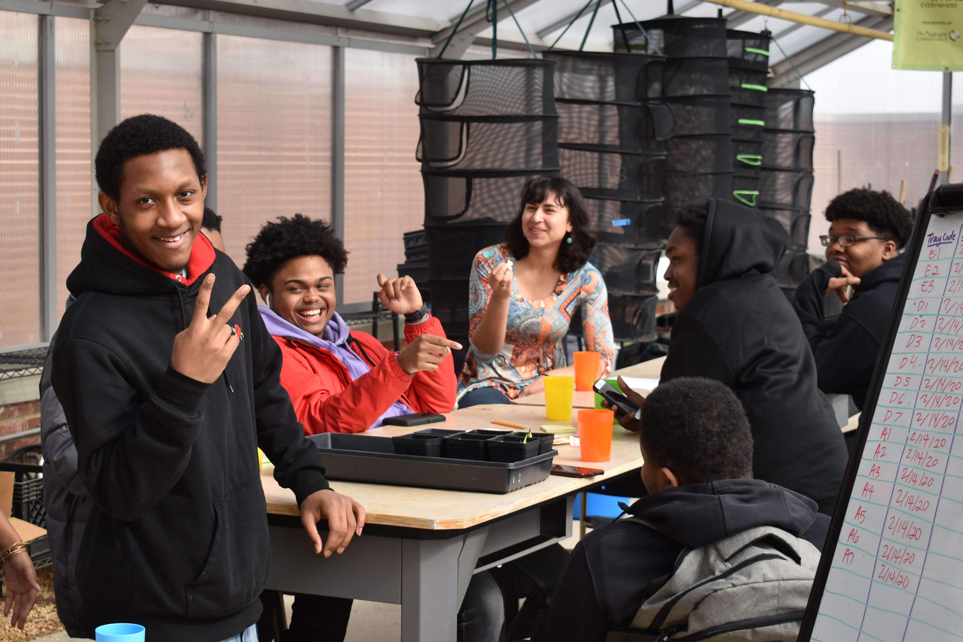 Mighty Greens Youth Staff smiling and chatting around a table during a team business meeting in a greenhouse