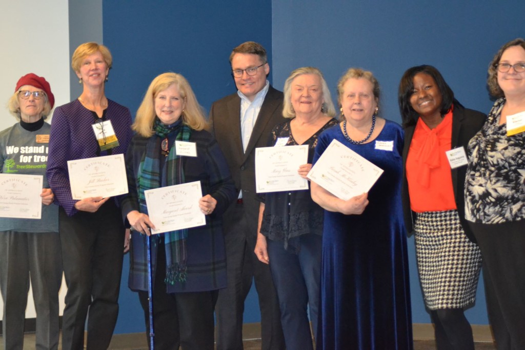 Photo of a group of EcoAction Arlington volunteers standing in a line, each holding up a certificate, at their recent volunteer celebration
